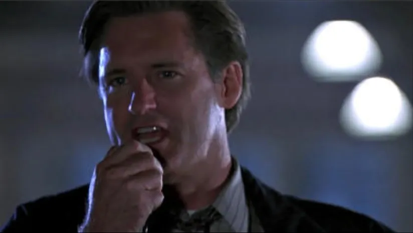 The President in Independence Day, speaking into a handheld microphone in a dimly lit hangar as he gives his speech to the pilots.