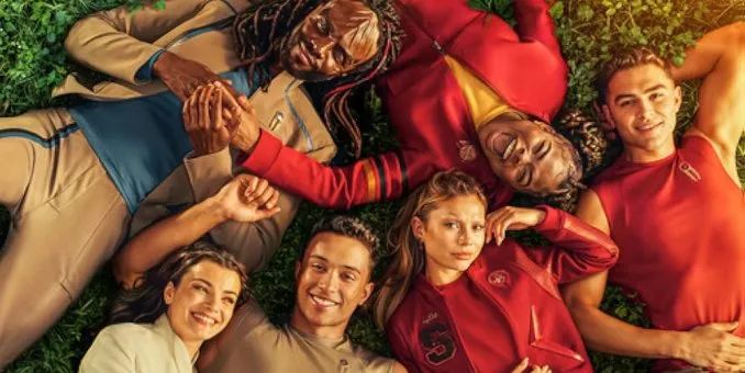 The Starfleet Academy cadets lying in a circle on the grass, heads together, smiling up at the camera.