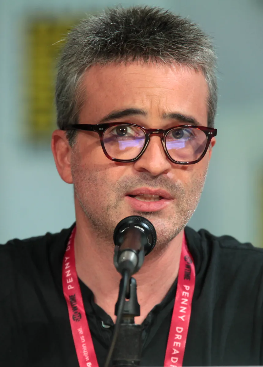 Alex Kurtzman speaking into a microphone at a convention panel.