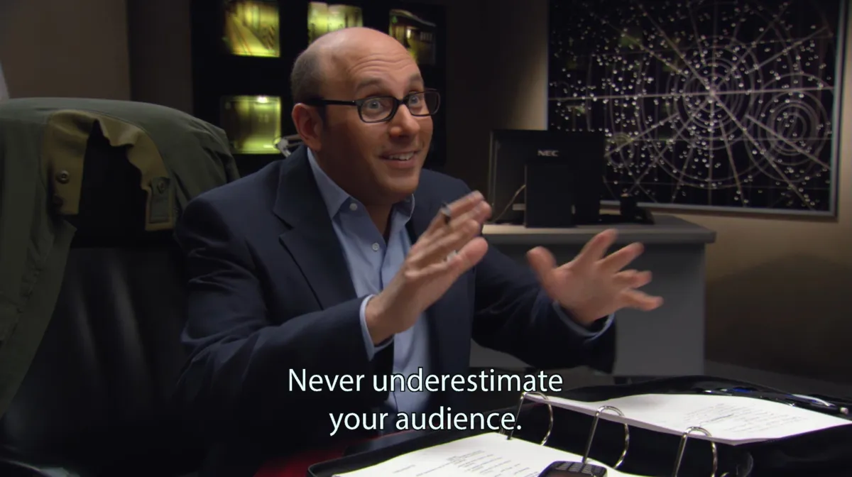 Marty gestures across the briefing table in Stargate SG-1's "200". Subtitle: "Never underestimate your audience."